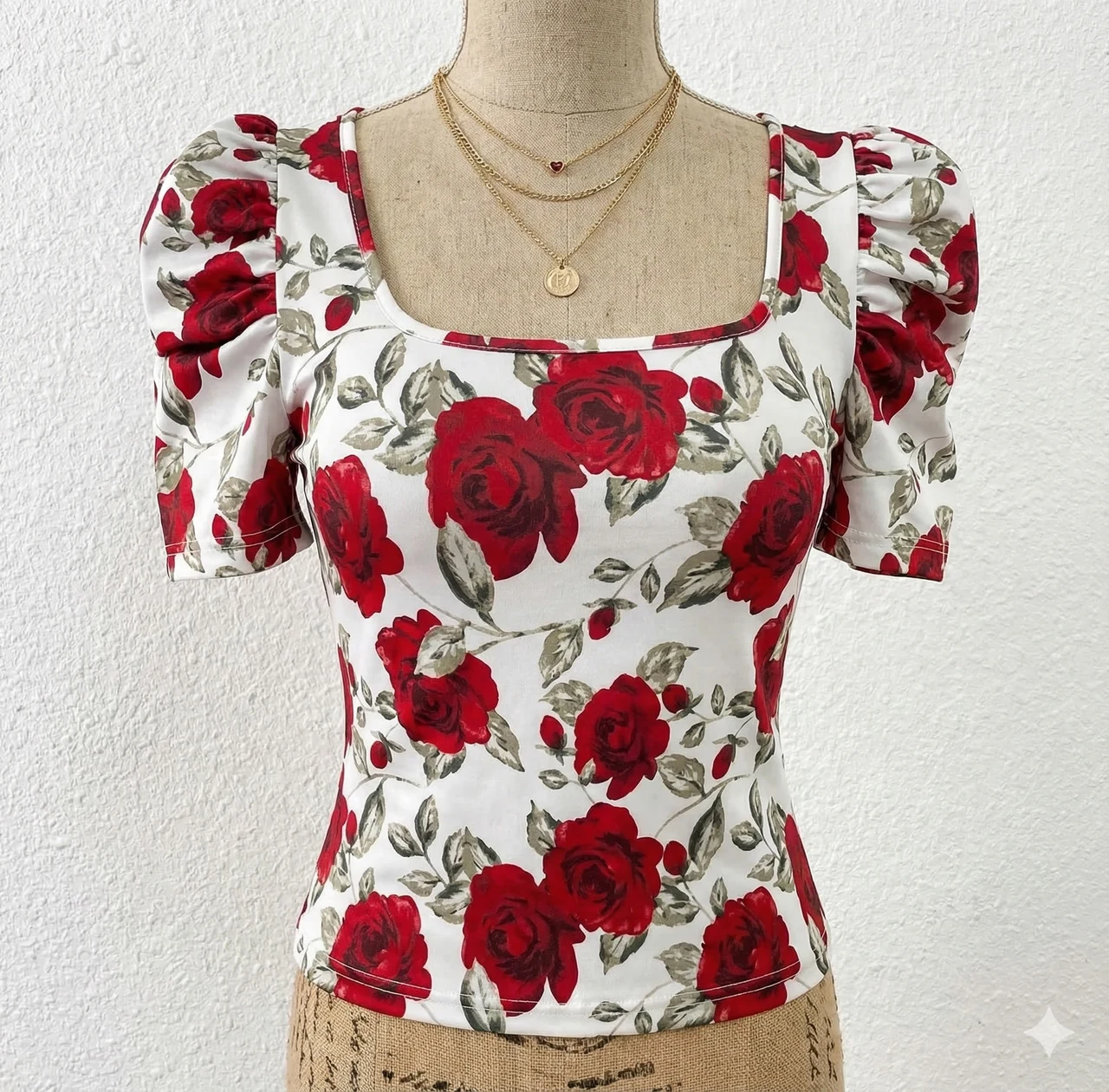 Blusa femenina culminada, confeccionada en tela ligera de acabado suave, con estampado floral de rosas rojas, manga corta abullonada, escote cuadrado y corte entallado.