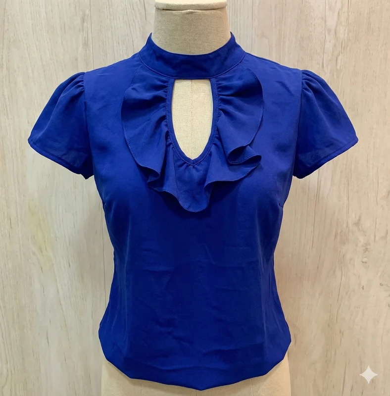 Blusa confeccionada en tela ligera de caída suave, color azul rey, con cuello alto, abertura frontal tipo gota, detalle de volantes en el pecho, manga corta y corte entallado, ideal para un 